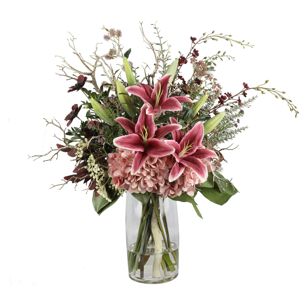 Pink Lily and Hydrangea Wild Artificial Arrangement with deep pink oriental lilies, blush pink hydrangea, dark burgundy orchids, silver branches, and wild foliage in a tall glass cylinder vase