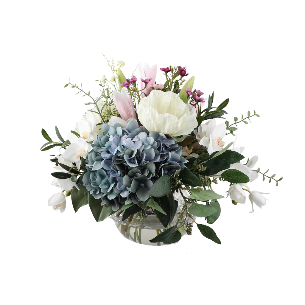 Hydrangea Dreams Artificial Bouquet with dusty blue hydrangea, white peony, pink tulips, cymbidium orchids, and magenta wax flowers in a glass fishbowl vase