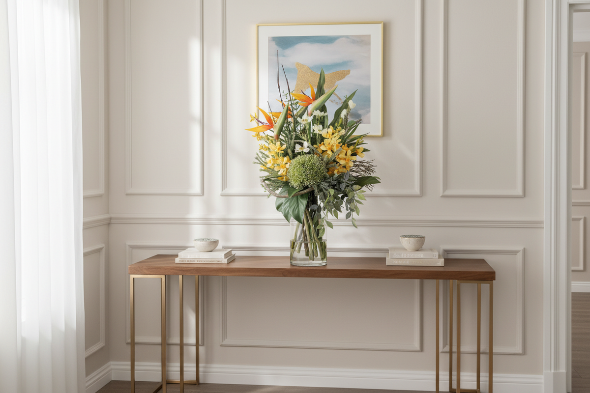 Bird of Paradise and Cymbidium Orchid medium artificial arrangement in a tall glass cylinder vase on an entryway console